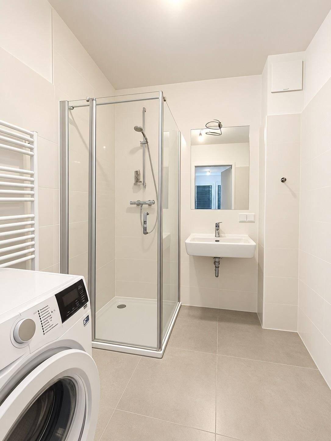 Modernes Badezimmer mit Duschkabine, Waschbecken, Waschmaschine und Handtuchheizkörper.