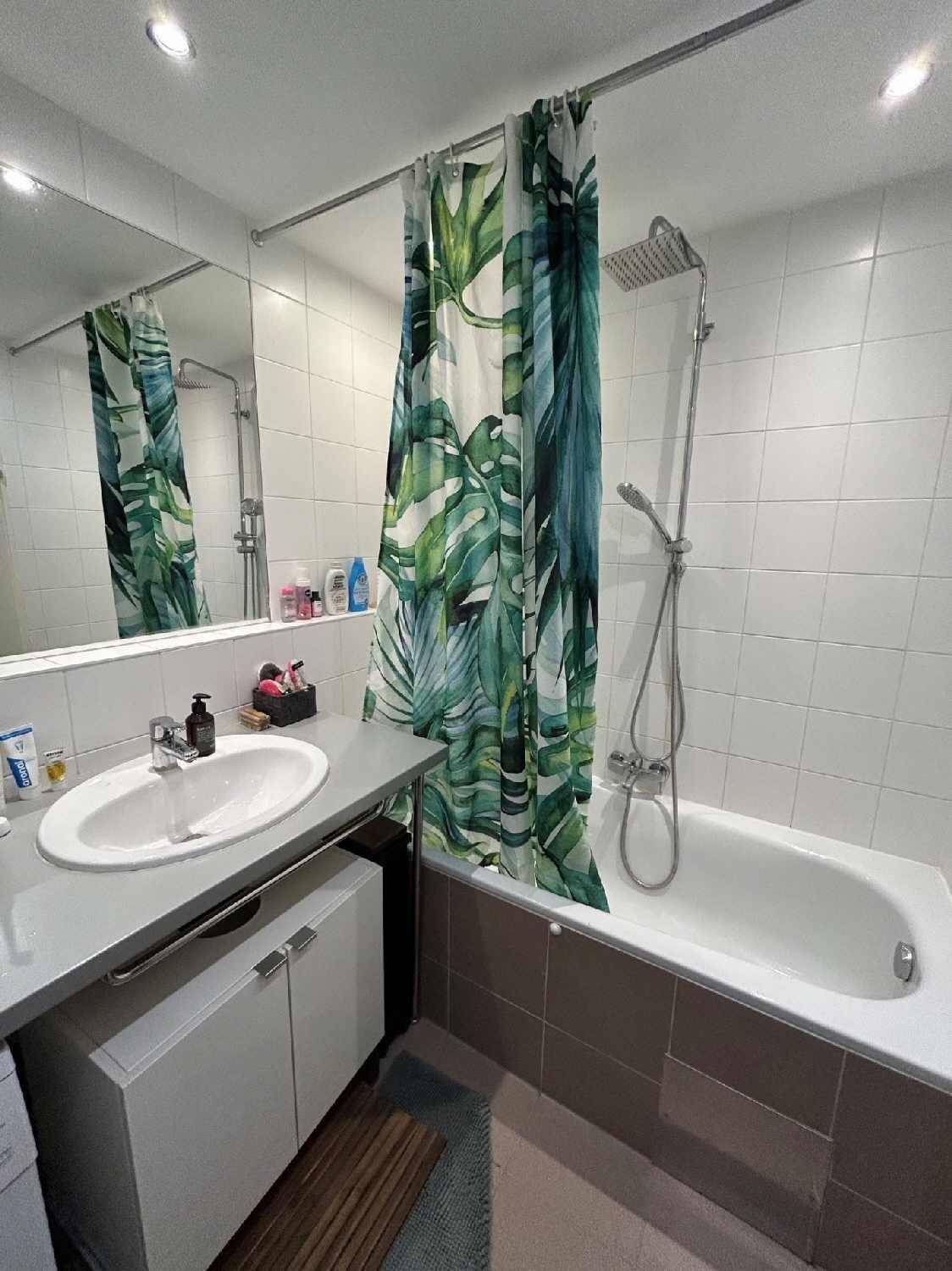 Badezimmer mit Badewanne, Duschvorhang und großem Spiegel über dem Waschbecken.