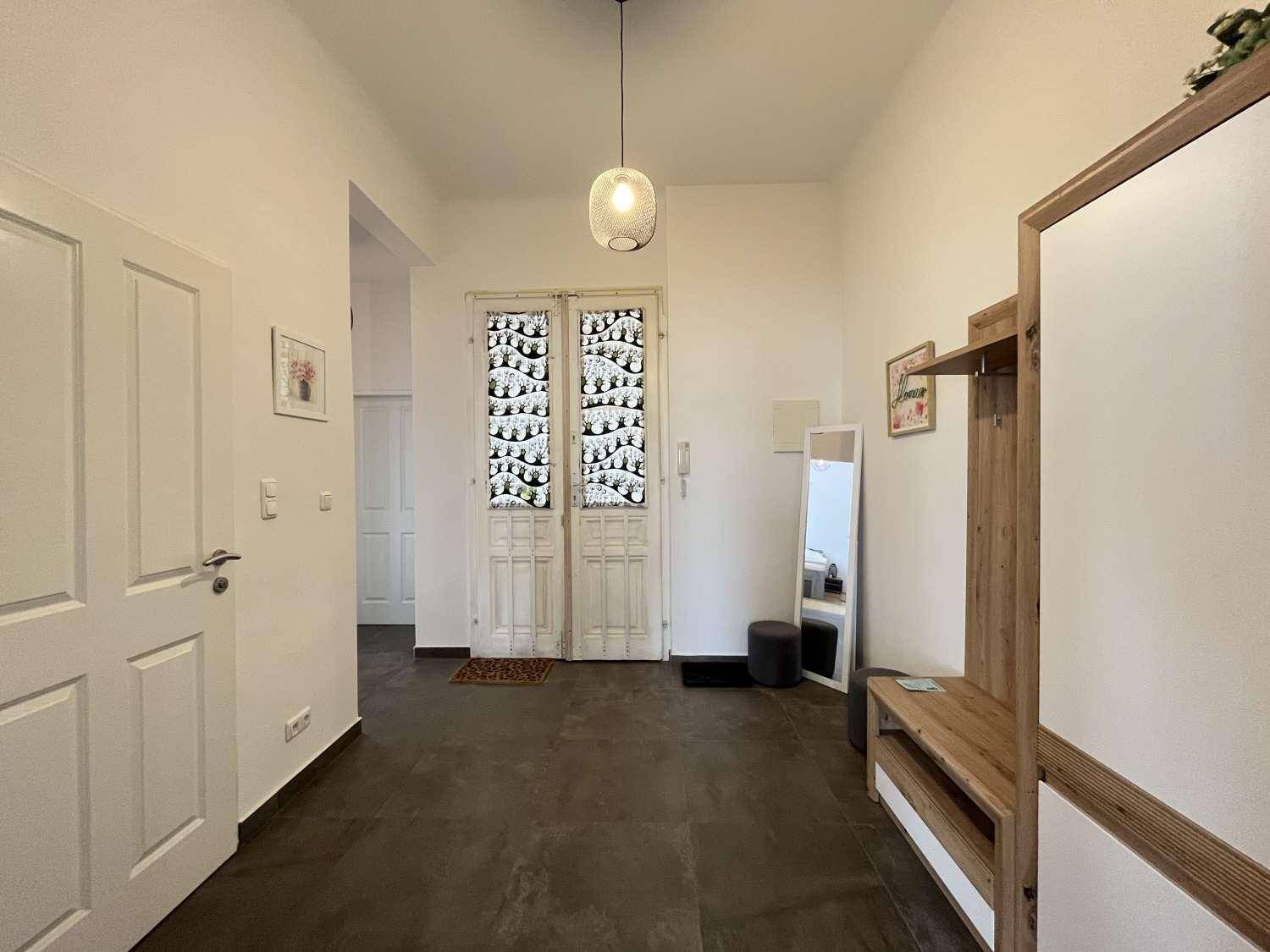 Geräumiger Flur mit dunklem Fliesenboden und Garderobe, der zur Eingangstür führt.