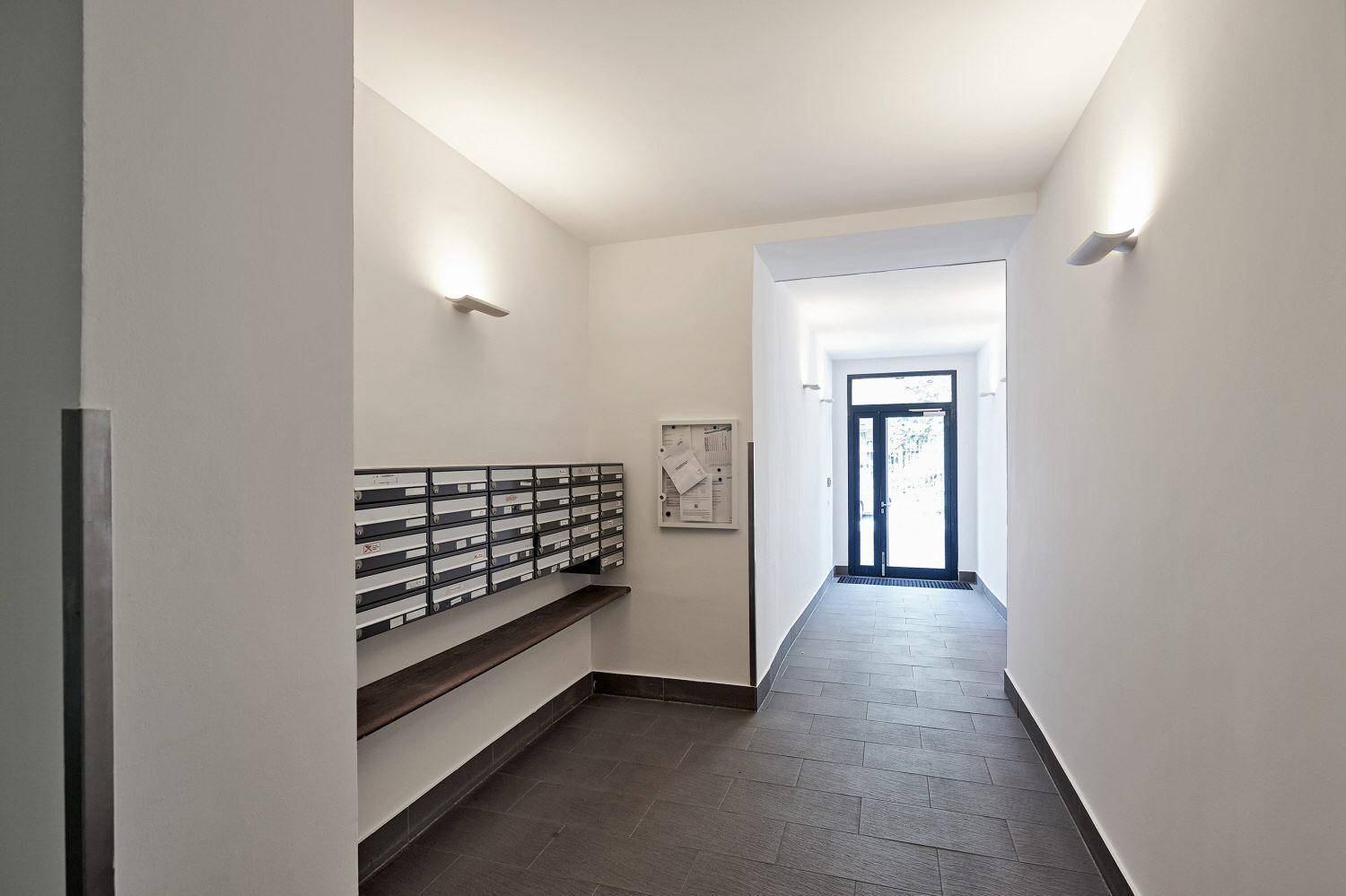 Eingangsbereich mit Briefkästen, Fliesenboden und Zugang zum Gebäude.