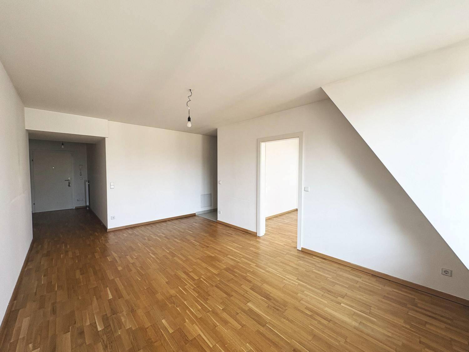 Geräumiger Wohnbereich mit hellem Parkettboden und Zugang zu angrenzenden Zimmern.