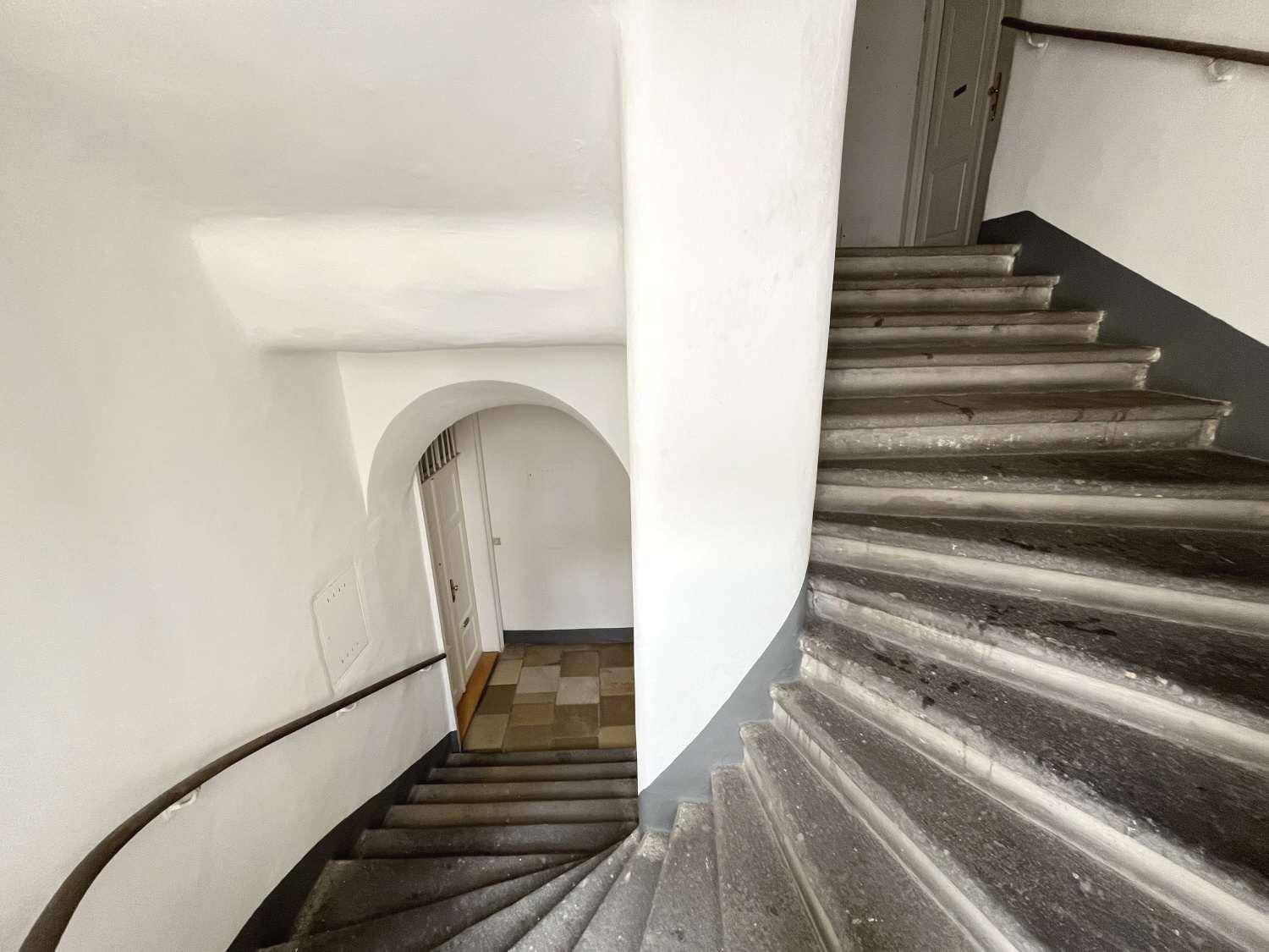 Historisches Treppenhaus mit Steinstufen und geschwungenem Geländer in einem Altbau.