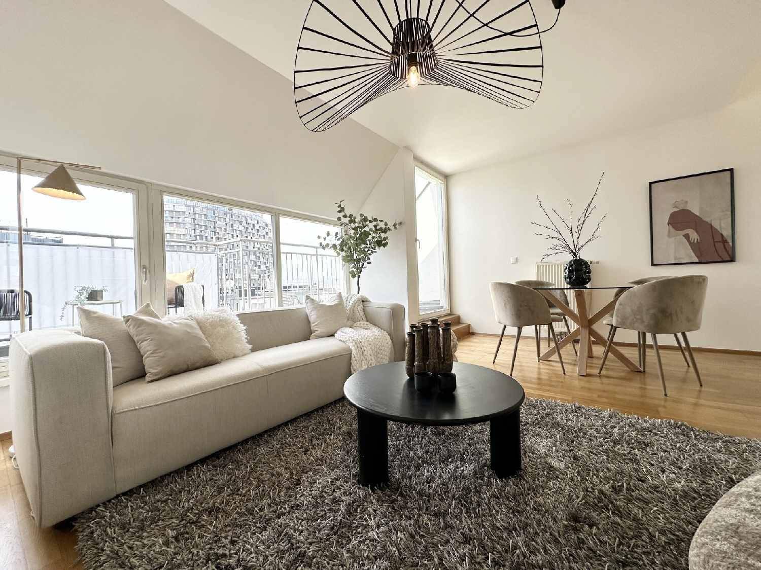 Offener Wohn-Essbereich mit modernem Design, Holzboden und direktem Zugang zum Balkon.
