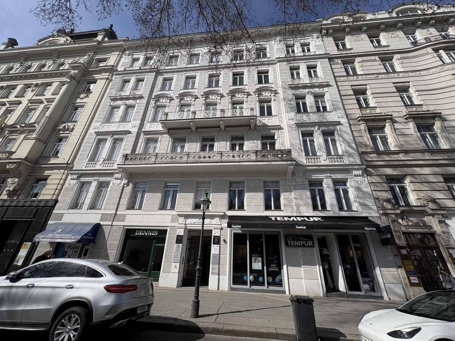 Historische Fassade eines Gebäudes mit vielen Fenstern und Balkonen, an einer belebten Straße.
