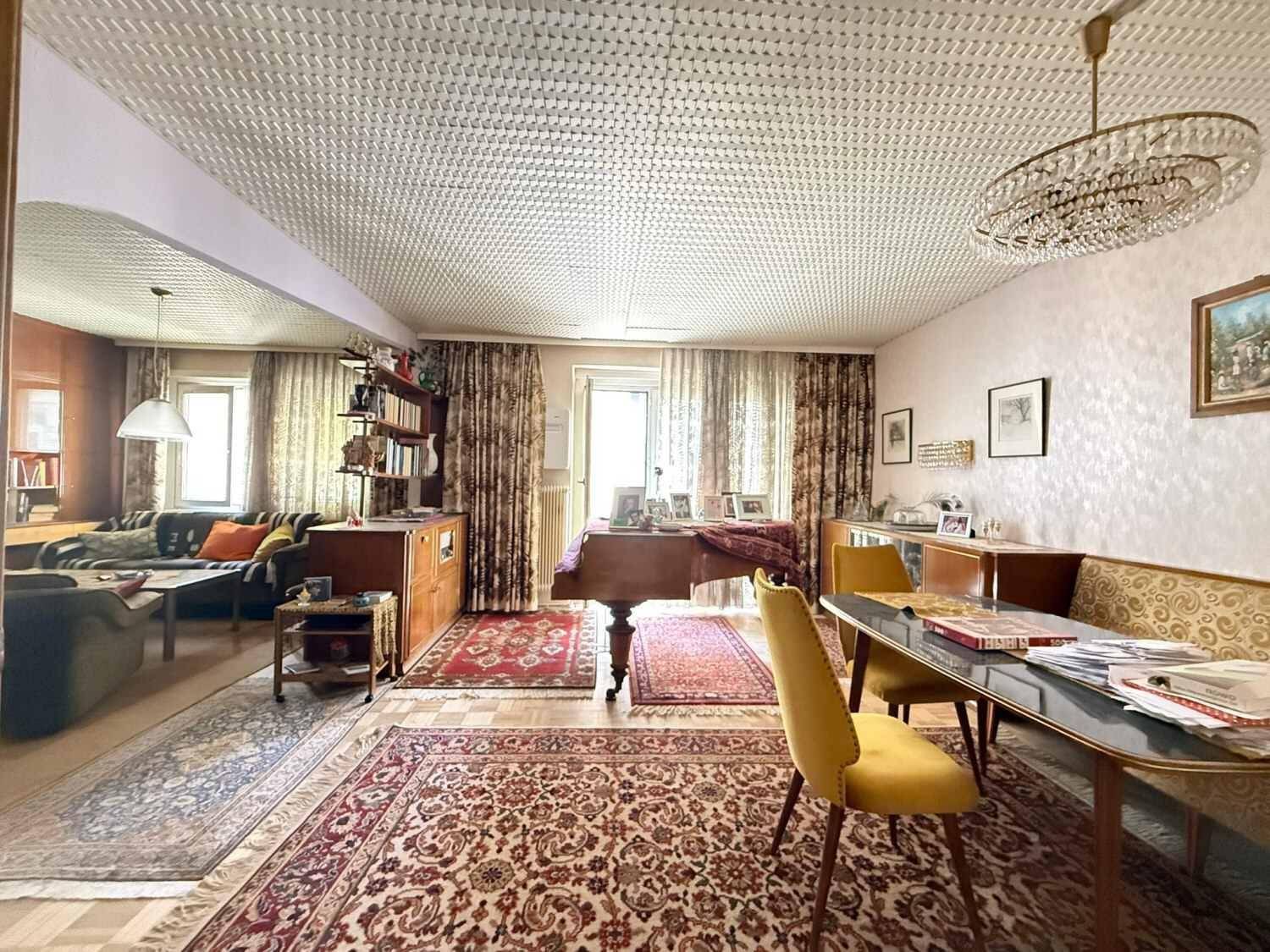 Geräumiger Wohn- und Essbereich mit traditionellen Teppichen, einem Klavier und einem Kronleuchter.