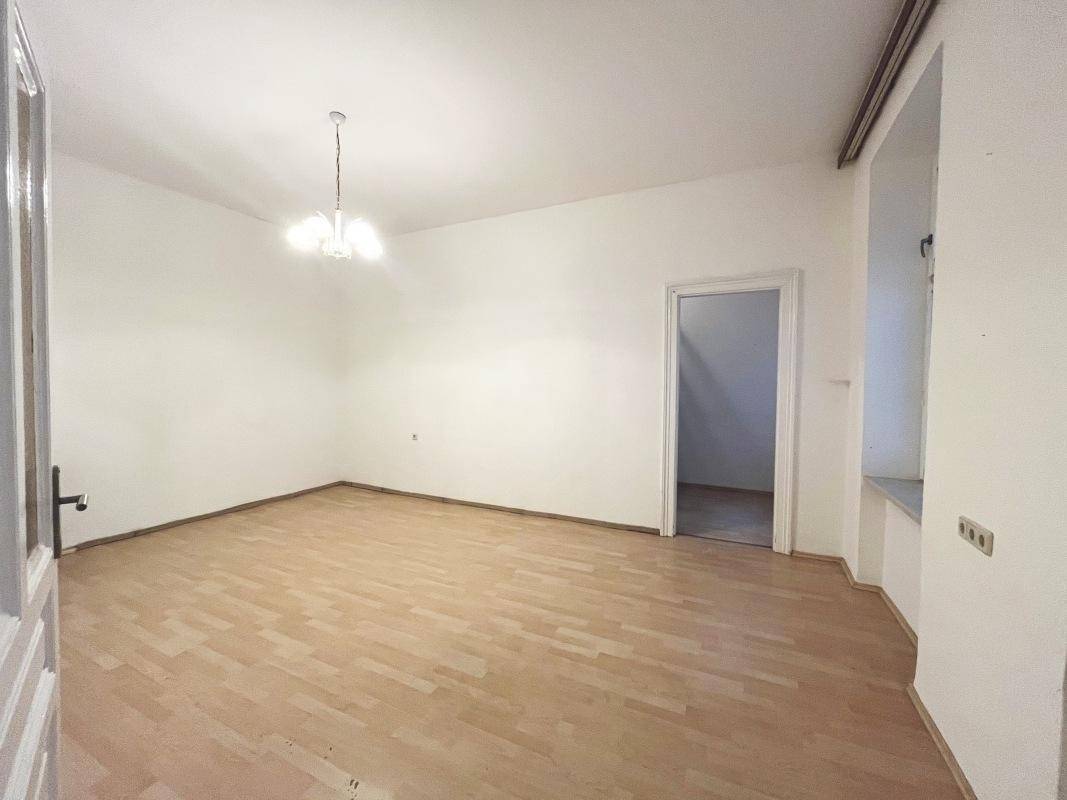 Geräumiges, helles Zimmer mit Holzboden und Zugang zu einem weiteren Raum.