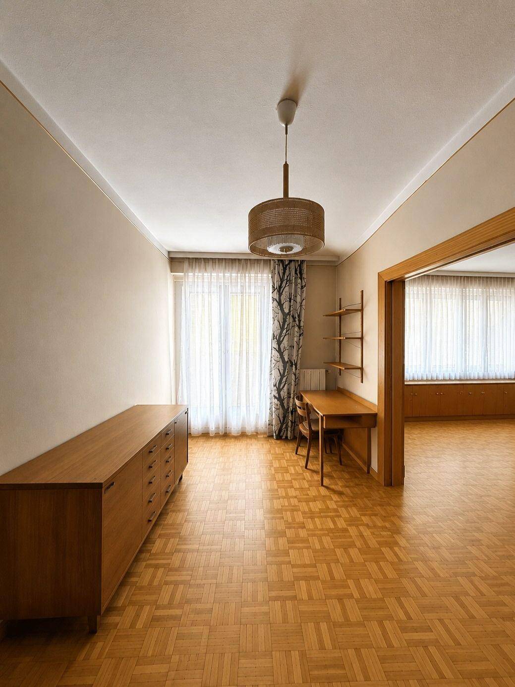 Heller Raum mit Parkettboden, einem Holzschrank und einem Schreibtisch, ideal als Büro nutzbar.