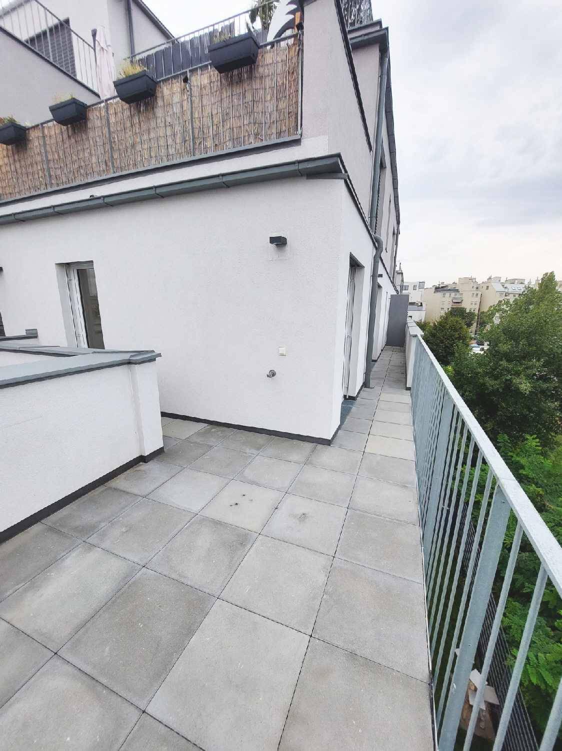 Außenbereich mit Fliesenboden und Blick auf die umliegenden Gebäude und den Himmel.
