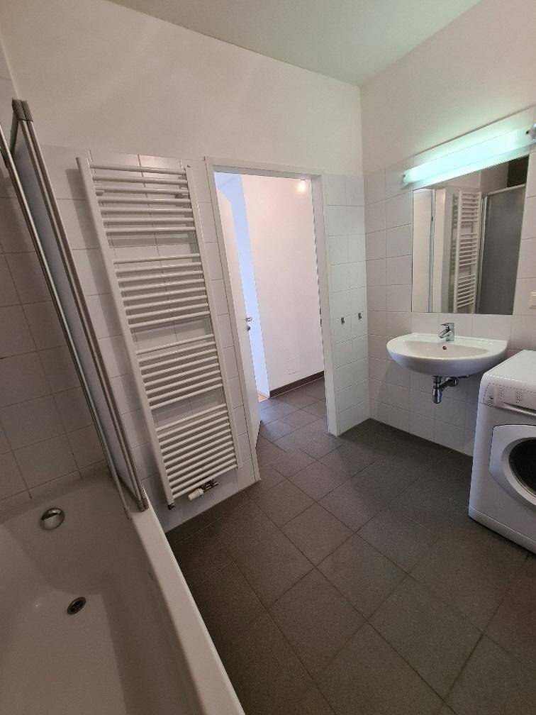 Badezimmer mit Badewanne, Waschbecken, Waschmaschine und beheiztem Handtuchhalter.