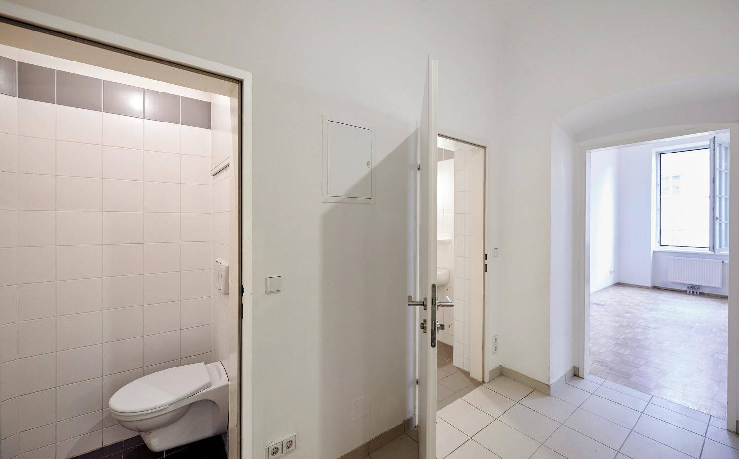Flur mit Zugang zu separatem WC und Badezimmer, alles hell gefliest.