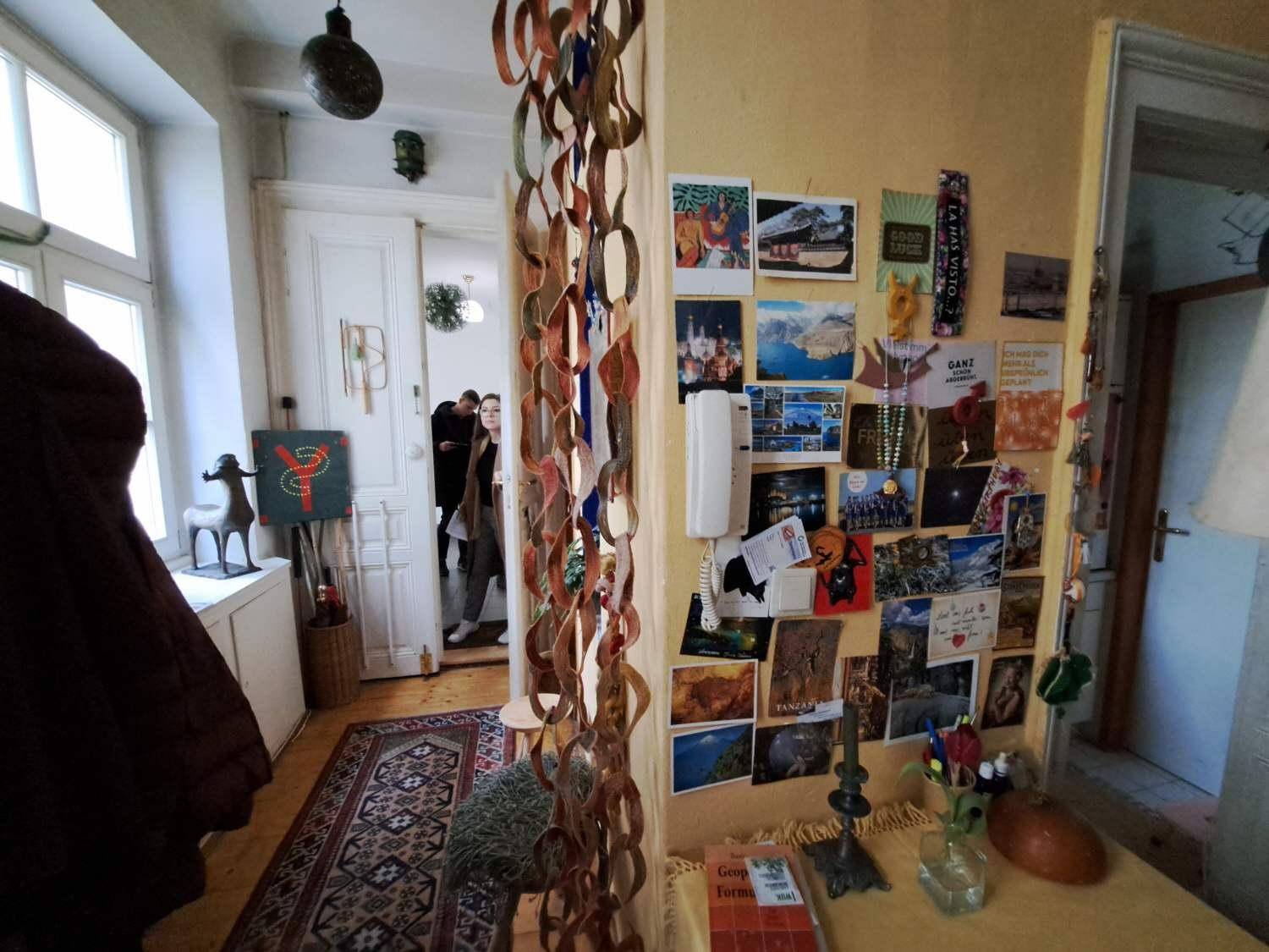 Flur mit Holzboden, Teppich und einer Wand voller Fotos und Dekorationen, die Persönlichkeit verleihen.