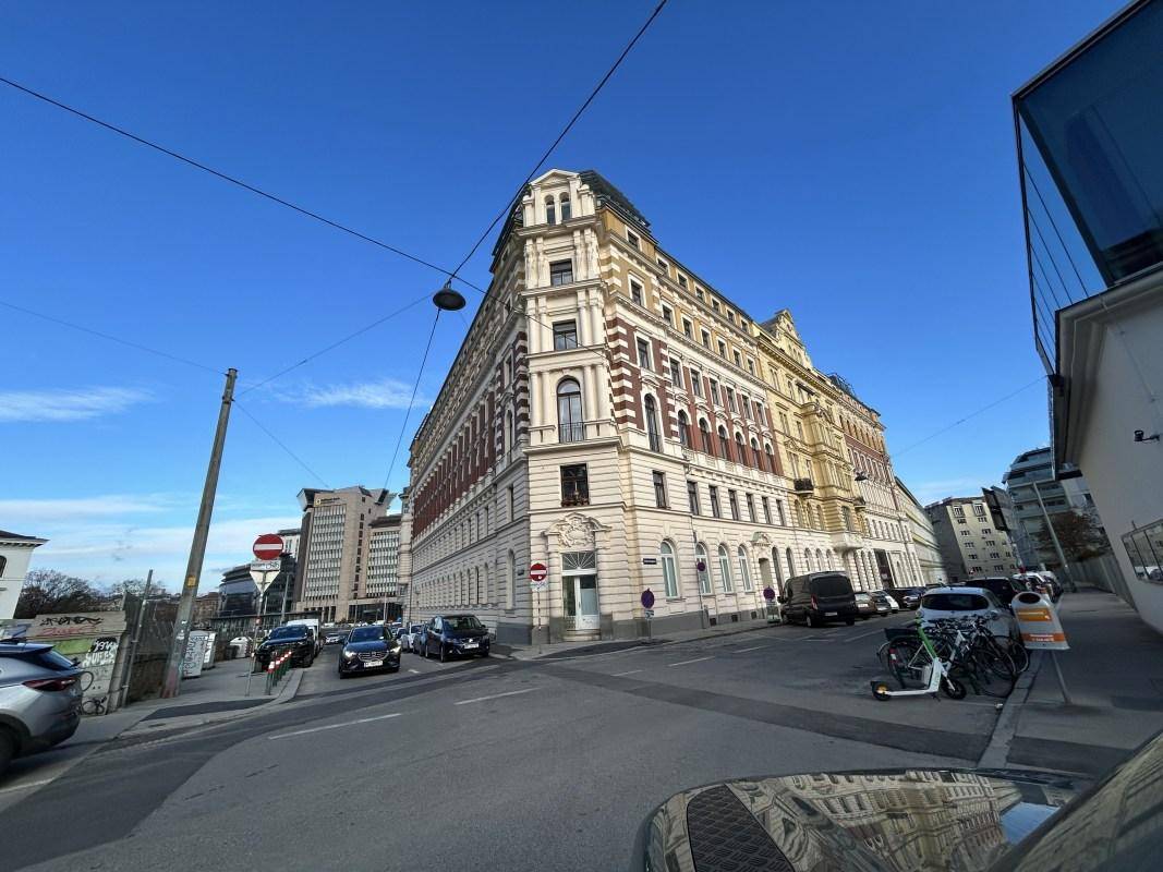 Historisches Eckgebäude mit reich verzierter Fassade an einer belebten Stadtkreuzung in Wien.