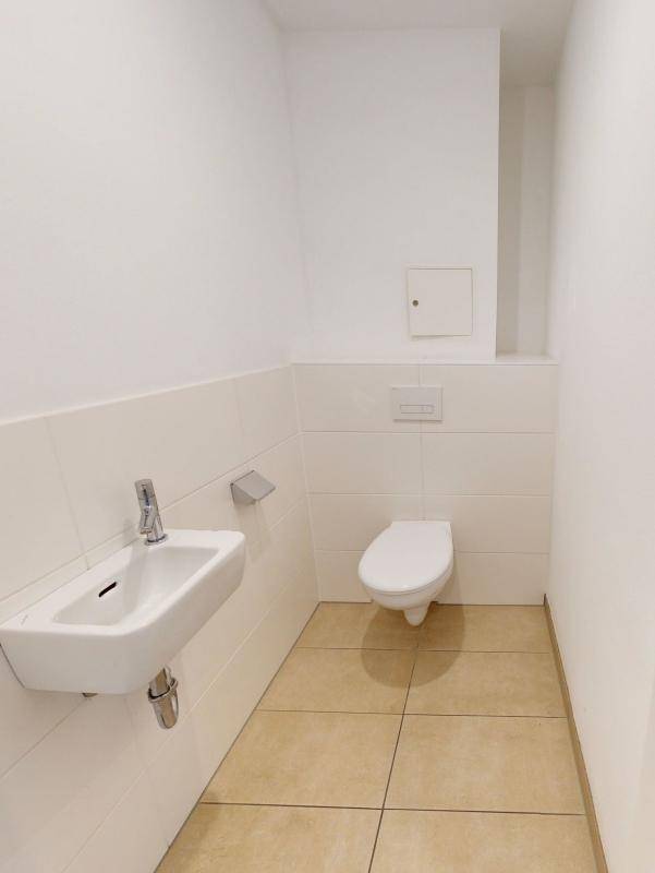 Modernes Gäste-WC mit wandhängender Toilette und kleinem Waschbecken.