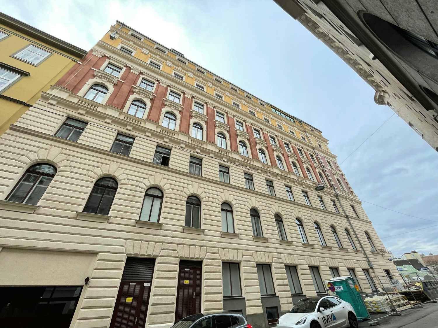 Detailansicht der imposanten Fassade eines Altbaus mit vielen Fenstern und traditionellen Verzierungen.