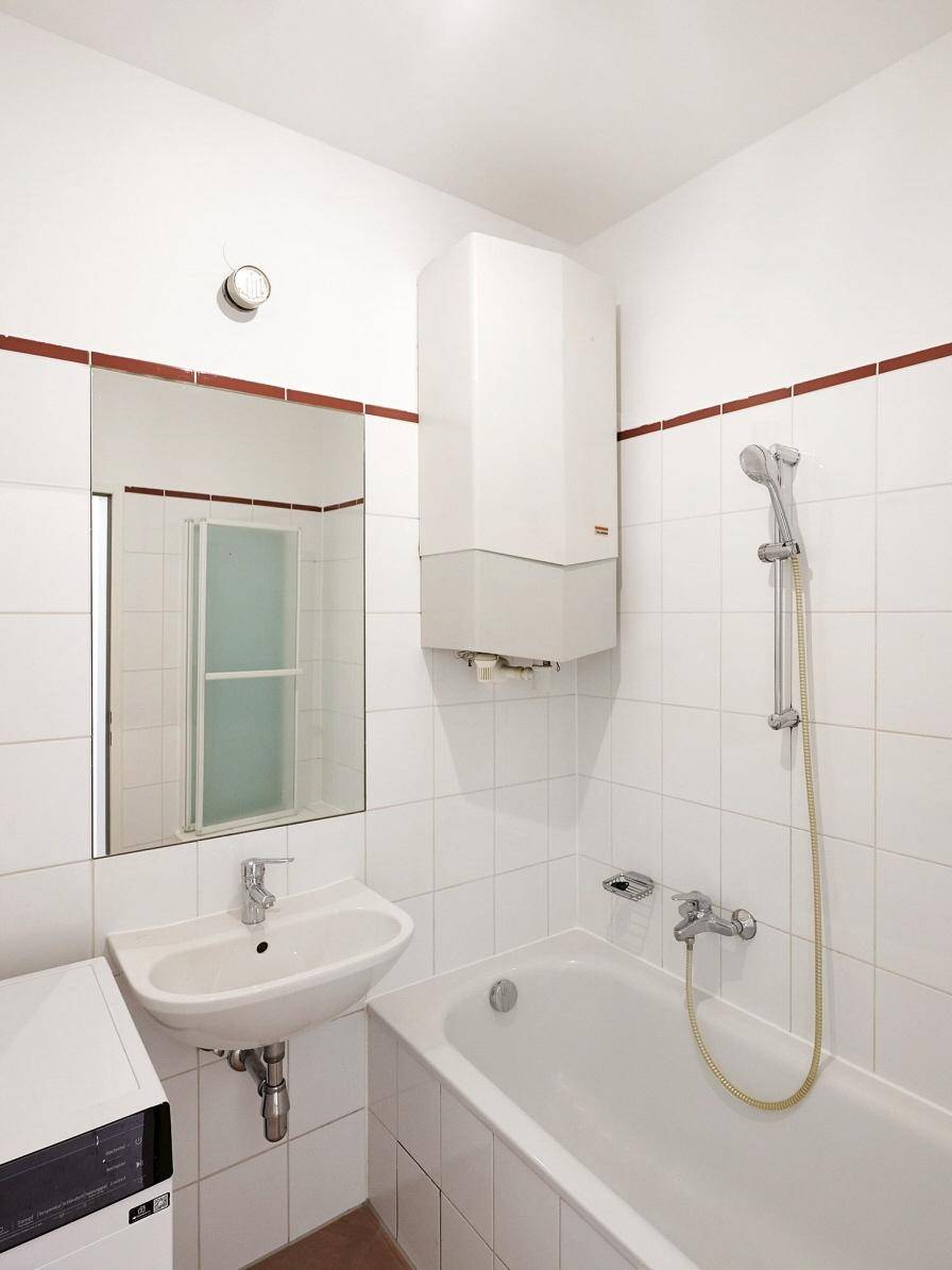 Gefliestes Badezimmer mit Badewanne, Waschbecken und Wandheizung, in gutem Zustand.