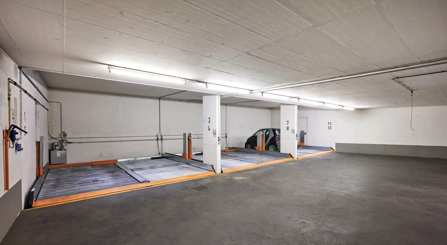 Tiefgarage mit mehreren Parkplätzen und mechanischen Parksystemen für Fahrzeuge.
