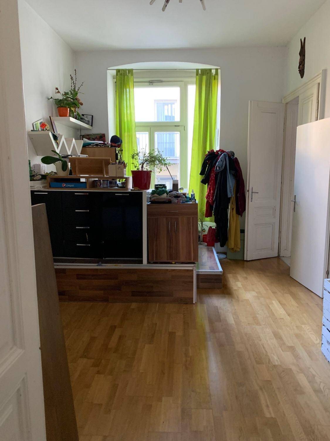 Heller Raum mit Holzboden, Fenster und einer erhöhten Ablagefläche, vielseitig nutzbar.