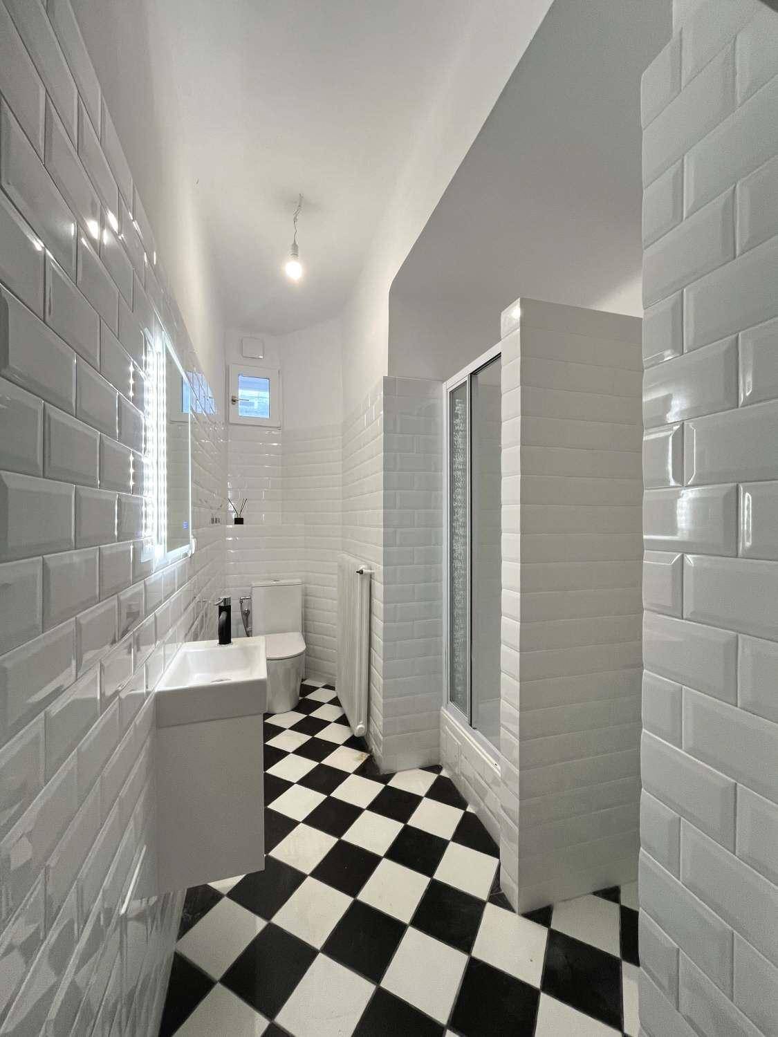Modernes Badezimmer mit schwarz-weißem Fliesenboden, Dusche und WC in minimalistischem Design.