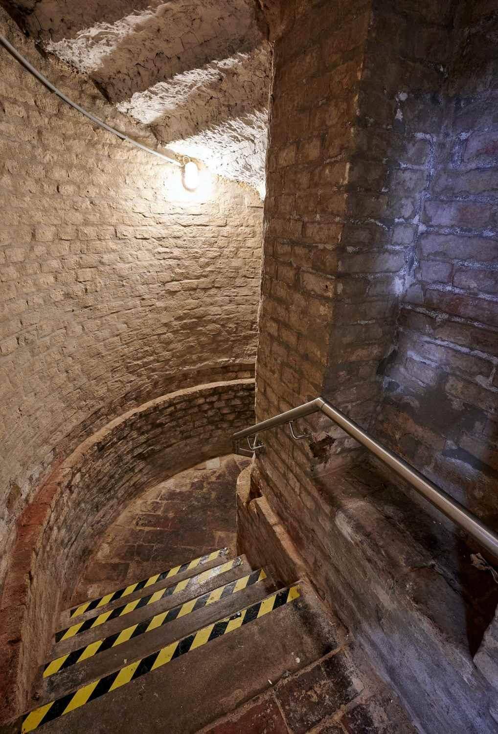 Historische Wendeltreppe aus Ziegelstein, die in einen Kellerbereich führt.