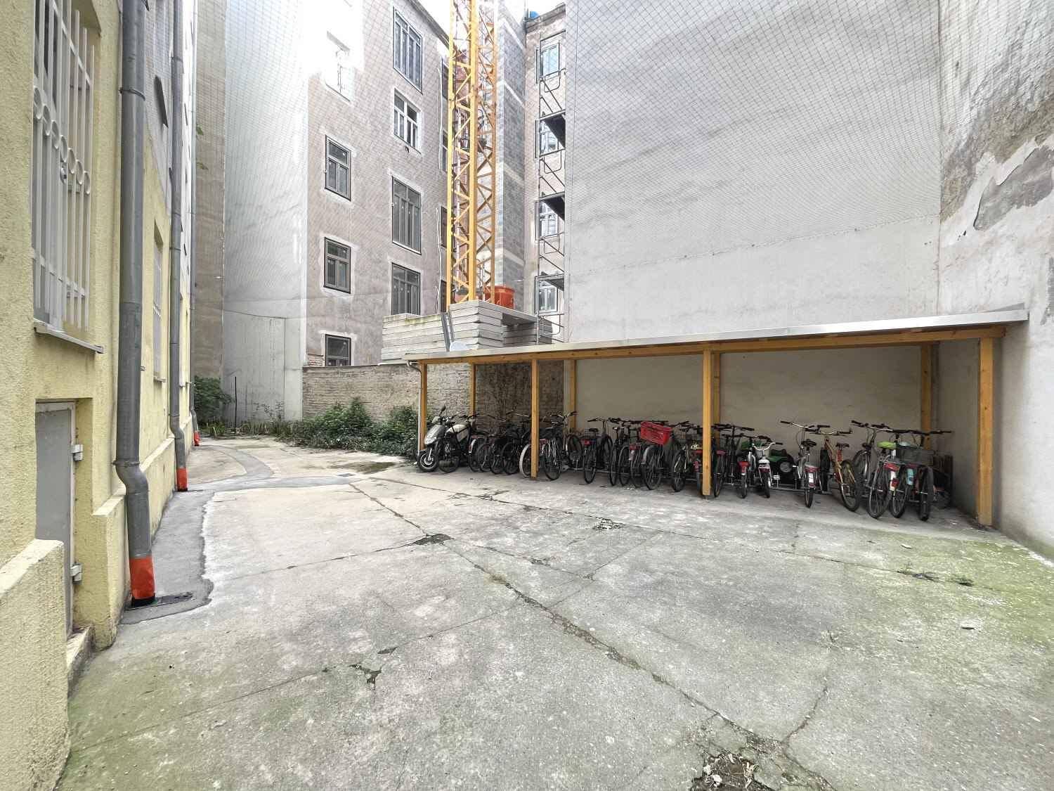 Innenhof mit überdachtem Fahrradabstellplatz und umliegenden Gebäudefassaden.