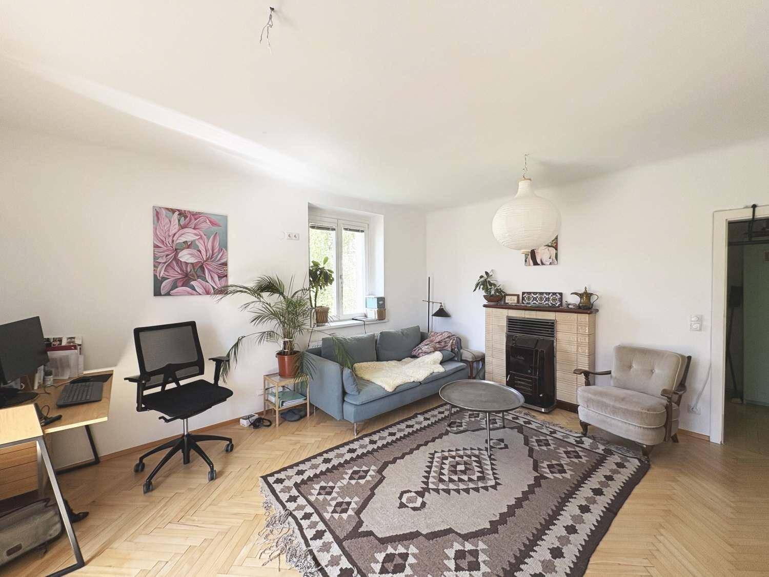 Helles Wohnzimmer mit Fischgrätparkett, einem Kaminofen und gemütlicher Sitzecke.