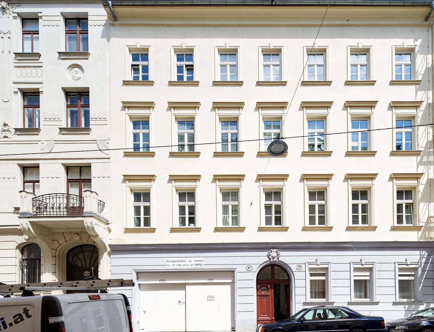 Klassische Fassade eines Wohngebäudes mit vielen Fenstern, Garagentor und historischem Eingangsbereich.