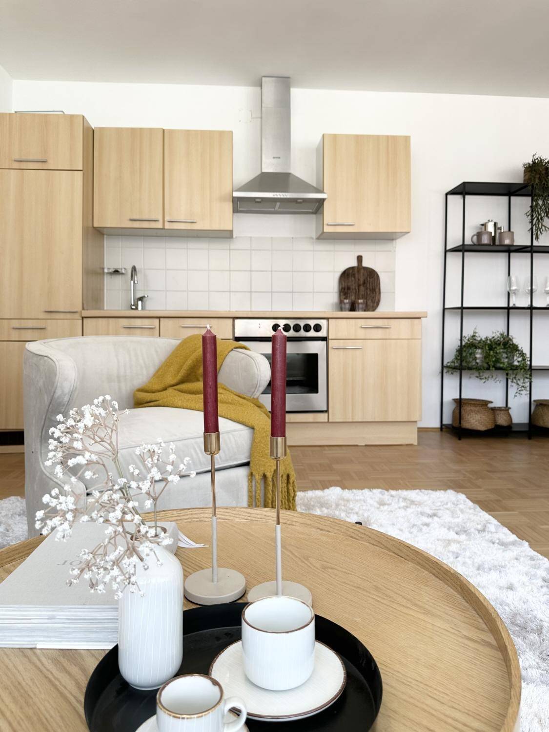 Detailansicht der modernen Küche mit Holzfronten, Kochfeld und stilvoller Dekoration im Vordergrund.