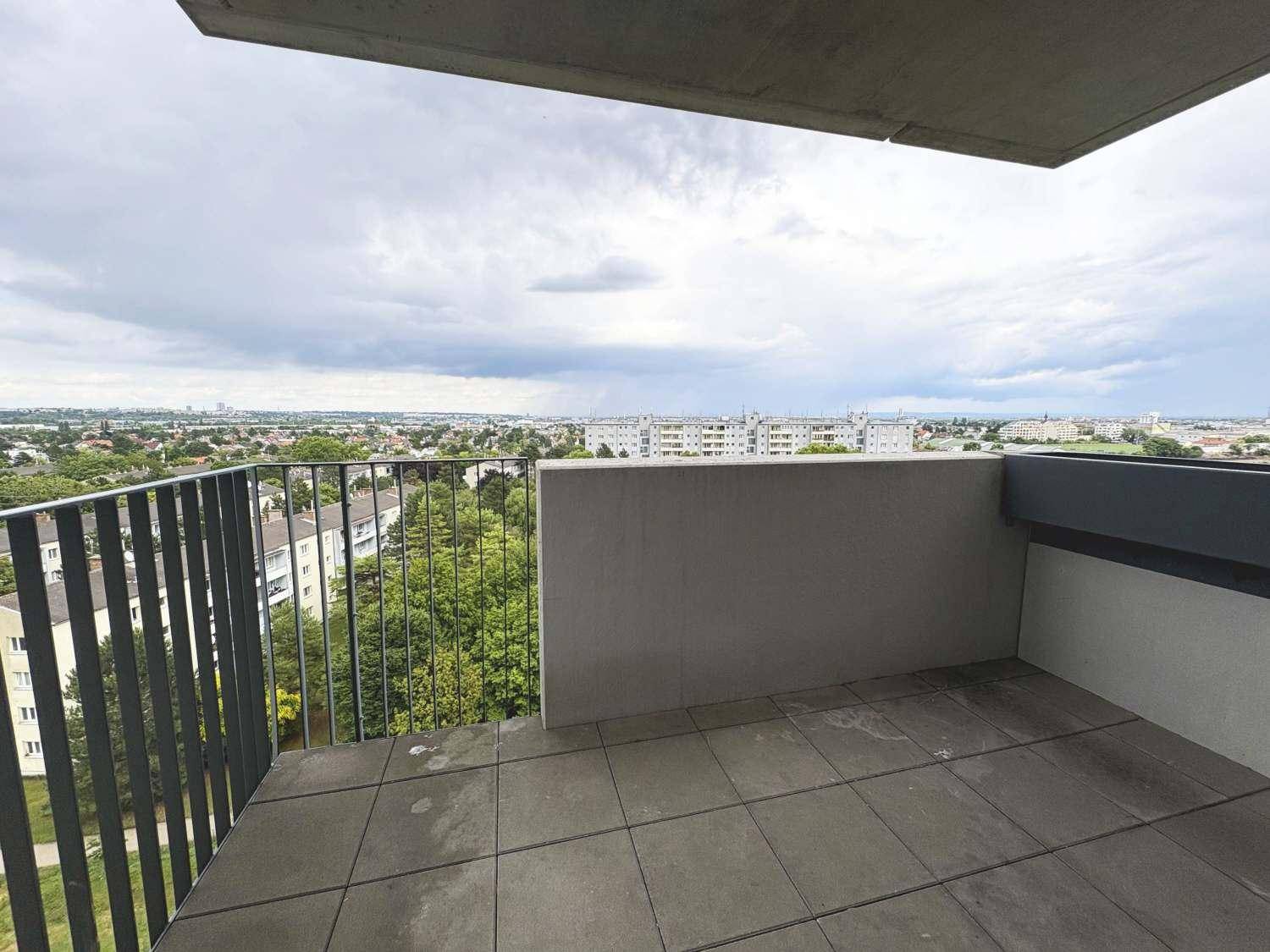 Geräumiger Balkon mit Fliesenboden und weitem Blick über die grüne Umgebung und Stadt.