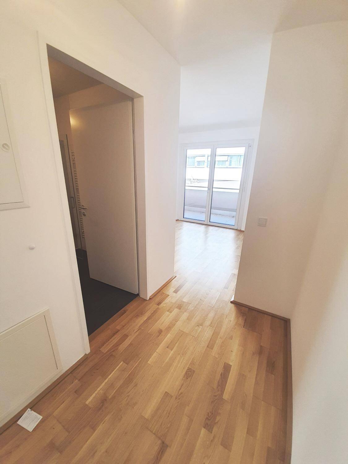 Heller Flur mit Parkettboden, der zum offenen Wohnbereich der Wohnung führt.