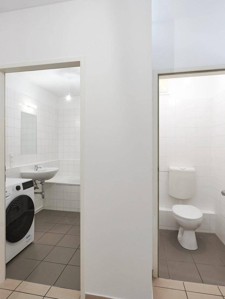 Eingangsbereich zu einem Badezimmer mit Waschmaschine und einem separaten WC.