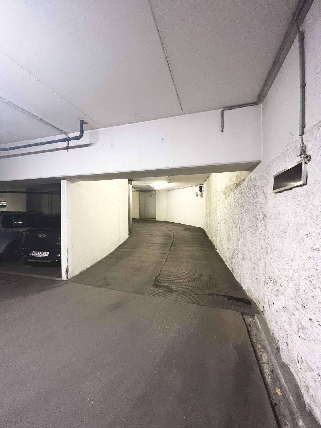 Zufahrtsrampe zu einer Tiefgarage mit Betonwänden und Beleuchtung.
