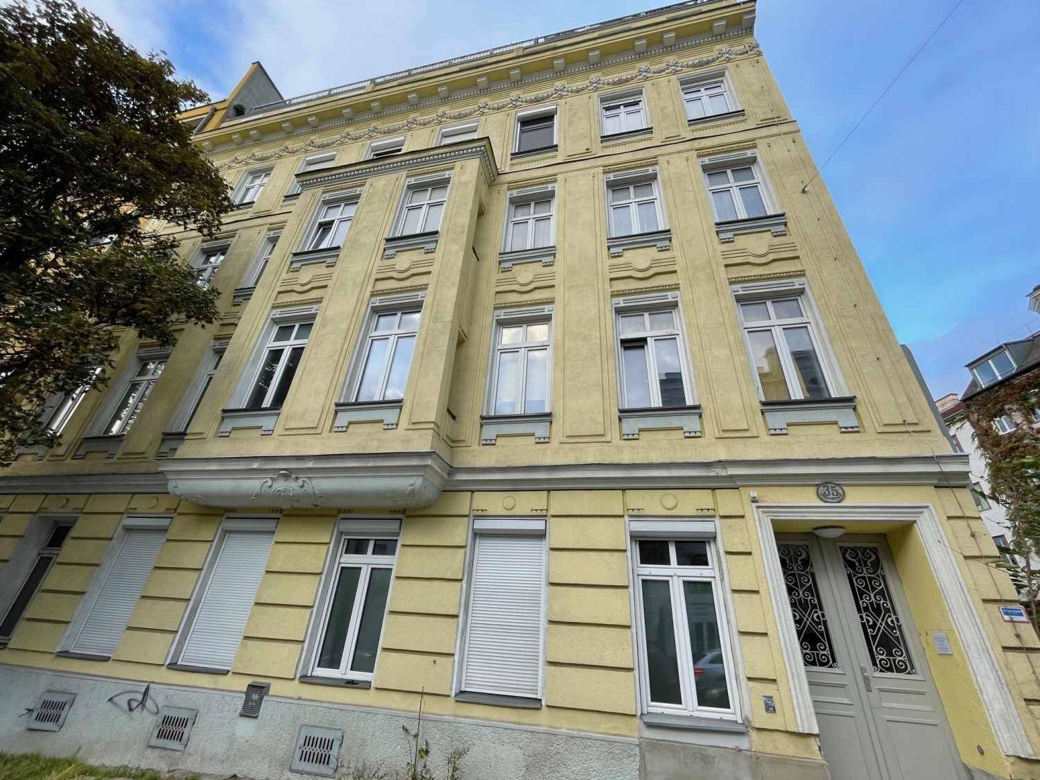 Die Fassade des historischen Gebäudes zeigt klassische Architekturdetails und mehrere Fensterreihen.