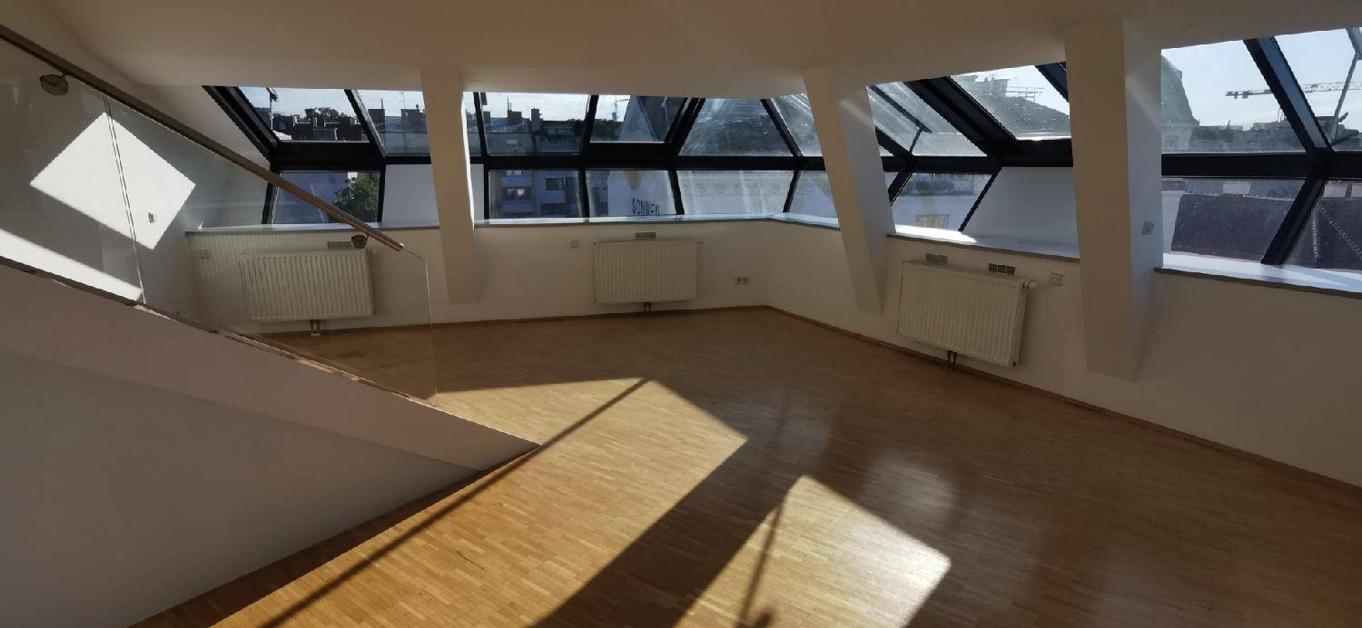 Lichtdurchfluteter Wohnbereich mit Holzparkett und schrägen Dachfenstern, schafft eine helle und moderne Umgebung.