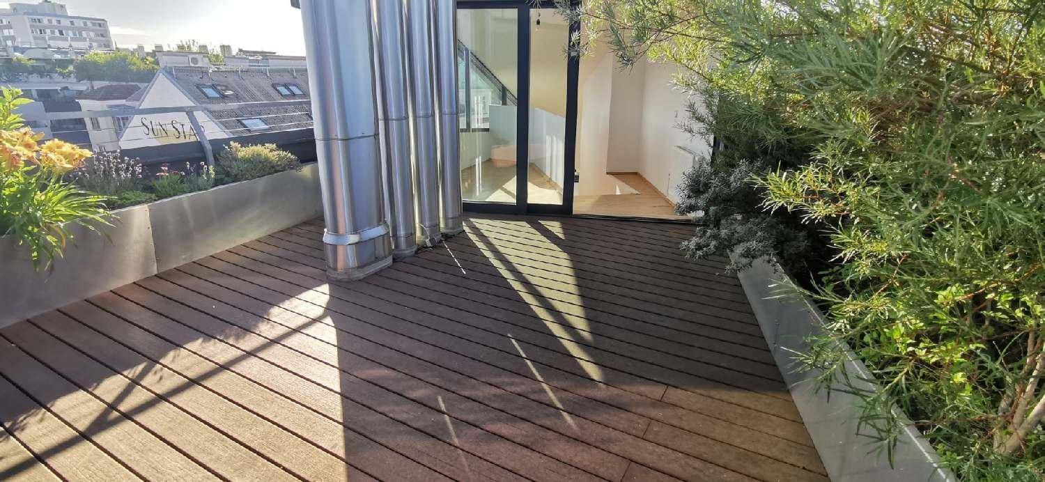 Attraktive Dachterrasse mit Holzbelag und Stadtblick, umgeben von grünen Pflanzen.