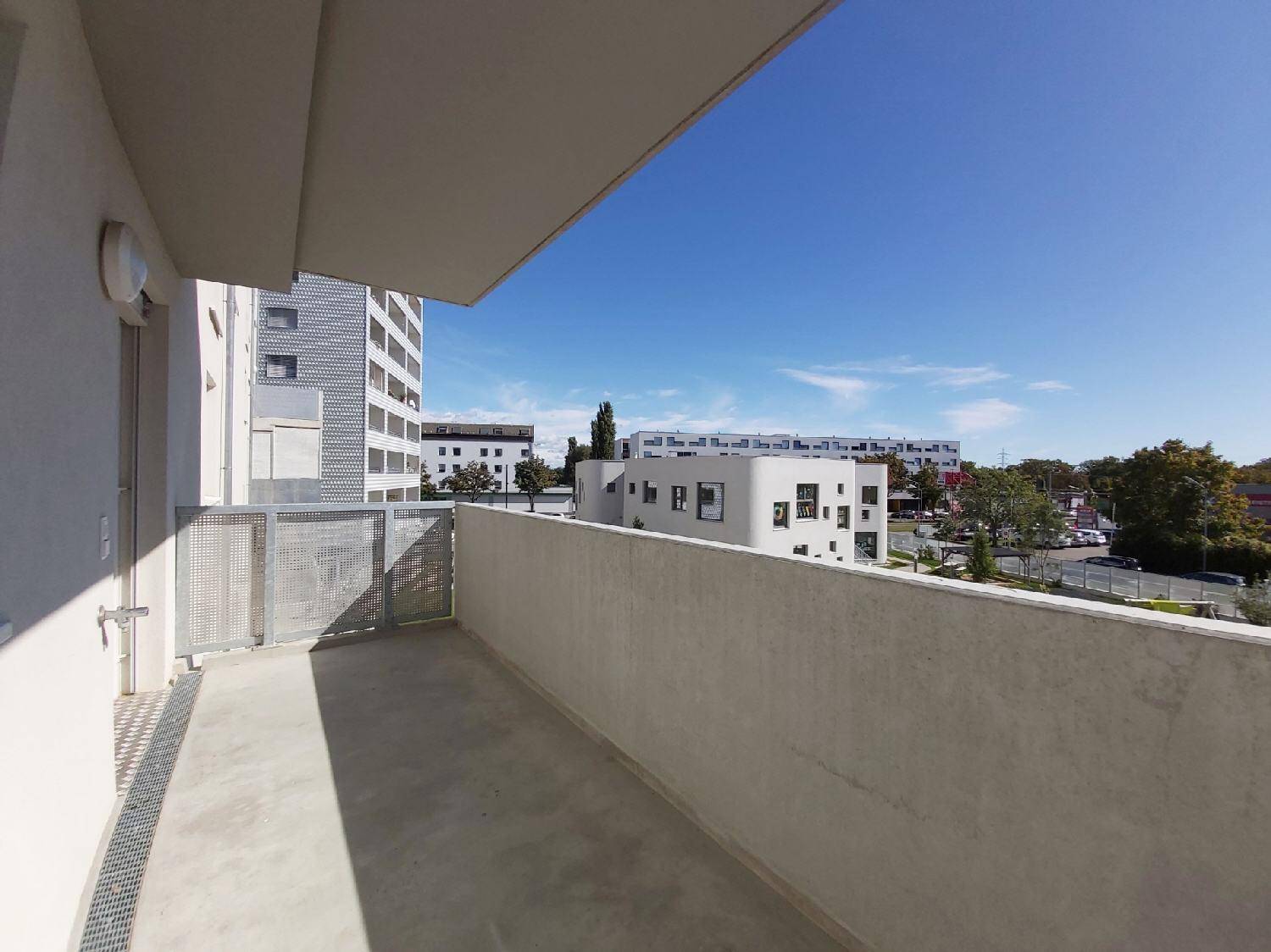 Unmöblierter Balkon mit Blick auf die umliegenden Gebäude und den weiten Himmel.