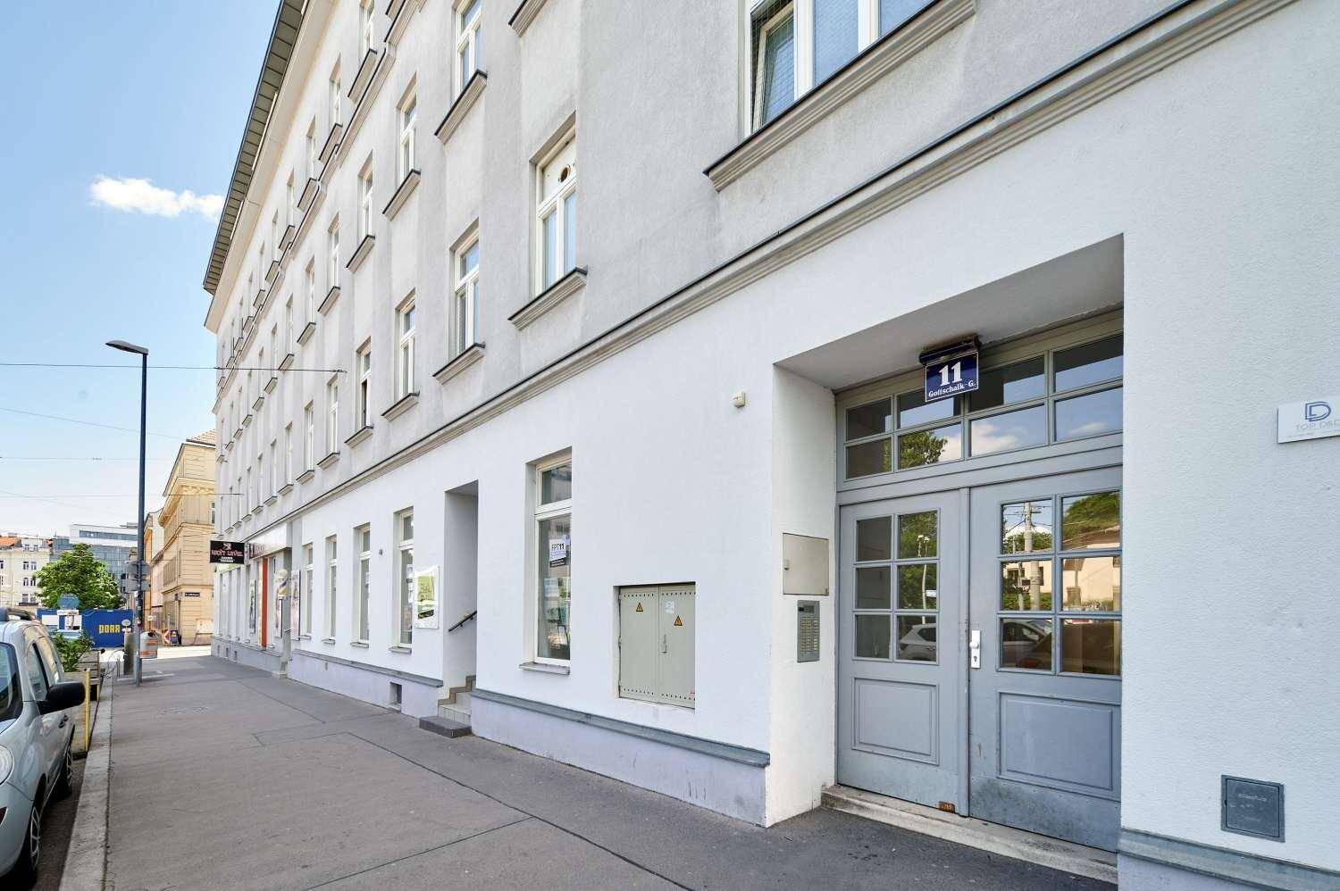 Fassade eines Wohngebäudes mit Eingangstür und Fenstern an einer städtischen Straße.