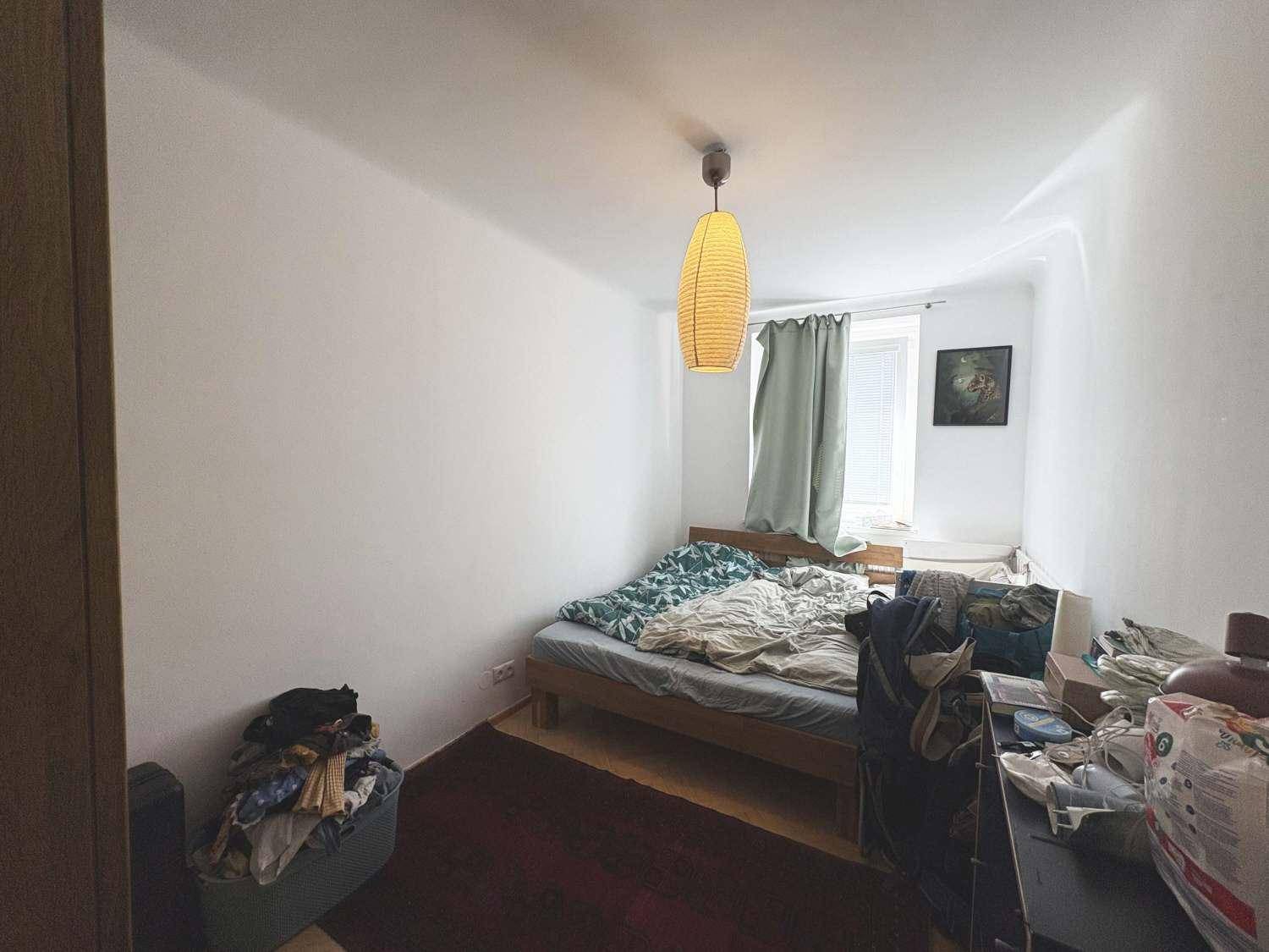 Schlafzimmer mit Holzbett, Vorhängen und einem Fenster für natürliches Licht.