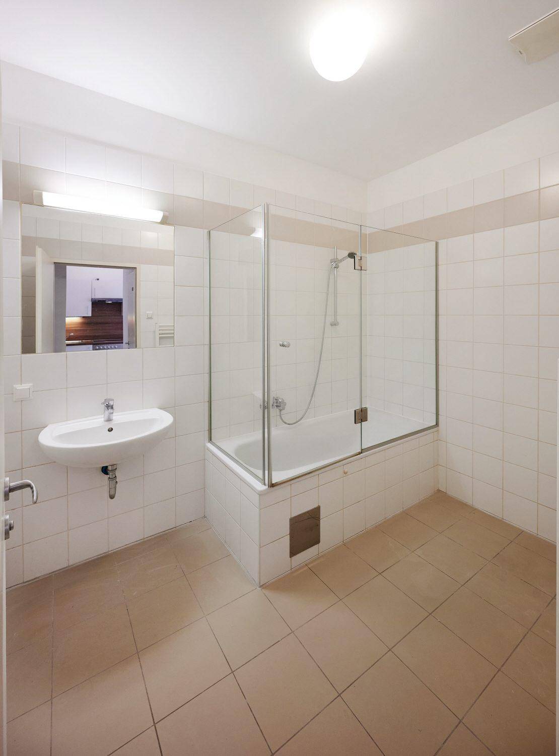 Badezimmer mit Badewanne, Duschabtrennung aus Glas und einem einzelnen Waschbecken.