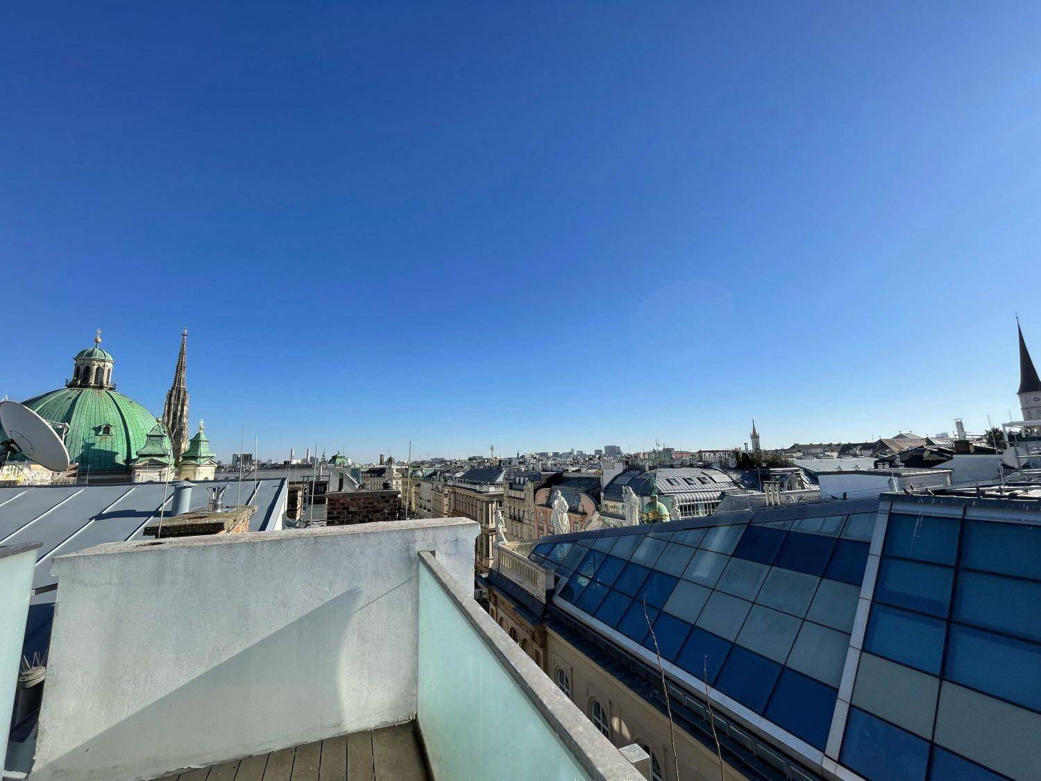 Panoramablick über die Dächer der Stadt mit historischen Kuppeln und moderner Architektur unter klarem Himmel.