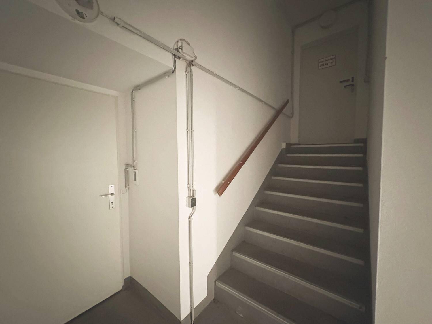 Einfaches Treppenhaus mit Holzhandlauf und robusten Stufen, führt zu weiteren Etagen.