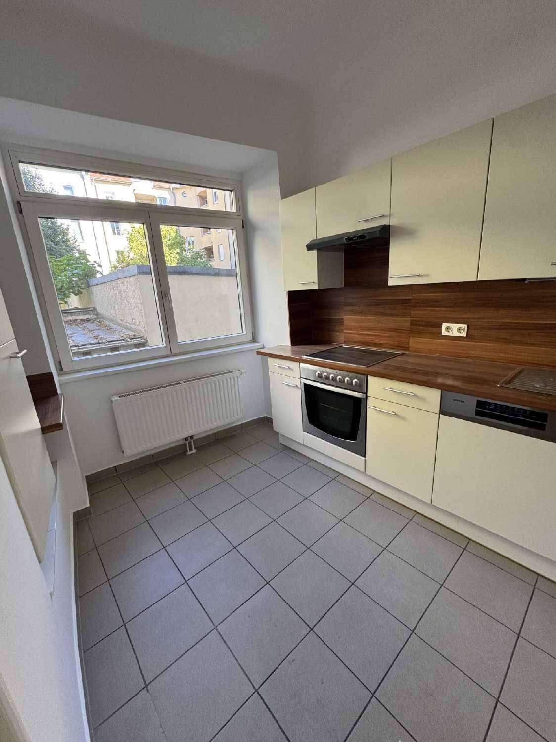 Funktionale Küche mit hellen Schränken, Holzoptik-Arbeitsplatte und Fliesenboden, mit Blick nach draußen.