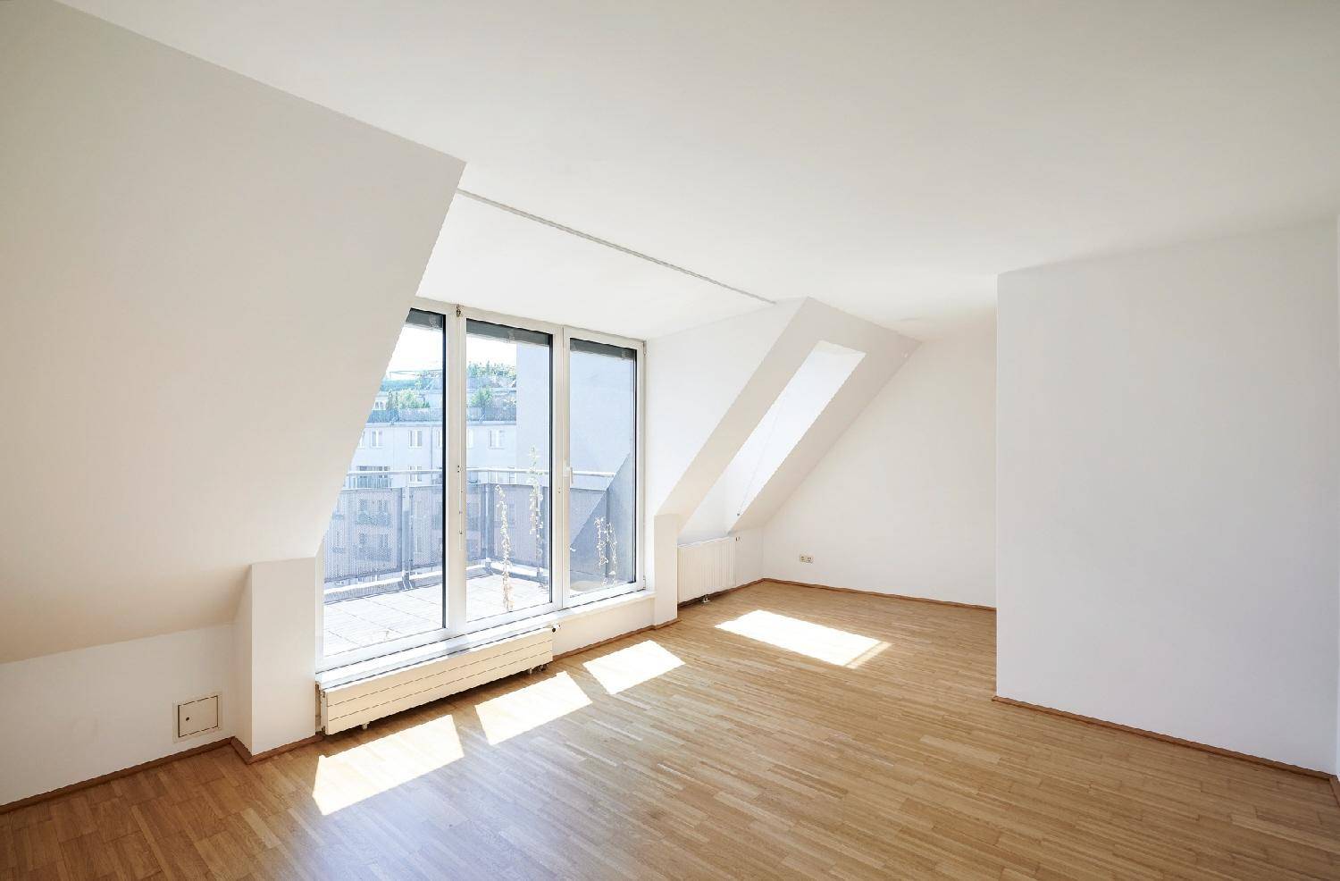 Helles Dachgeschosszimmer mit Holzboden, schrägen Wänden und Zugang zur Dachterrasse.