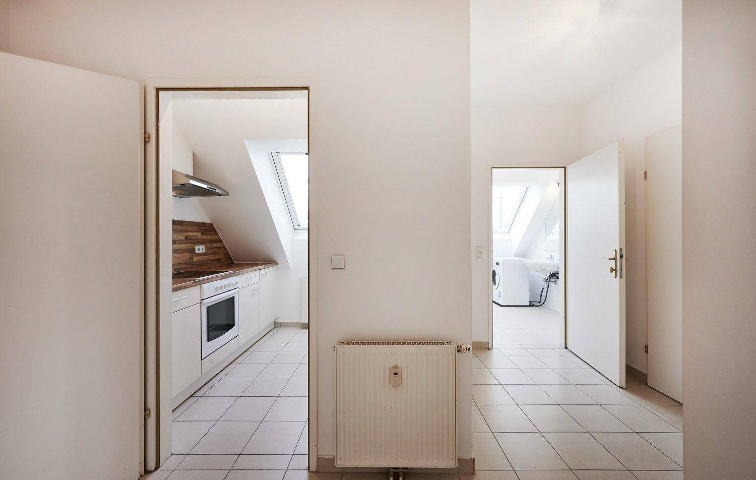 Heller Flur mit Fliesenboden und offenen Türen zu Küche und Badezimmer.