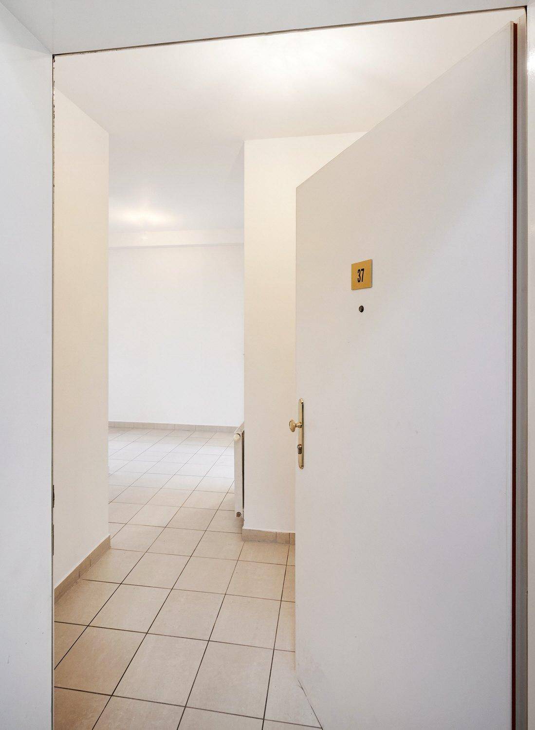 Heller Eingangsbereich mit Fliesenboden und offener Tür, die zu den Wohnräumen führt.