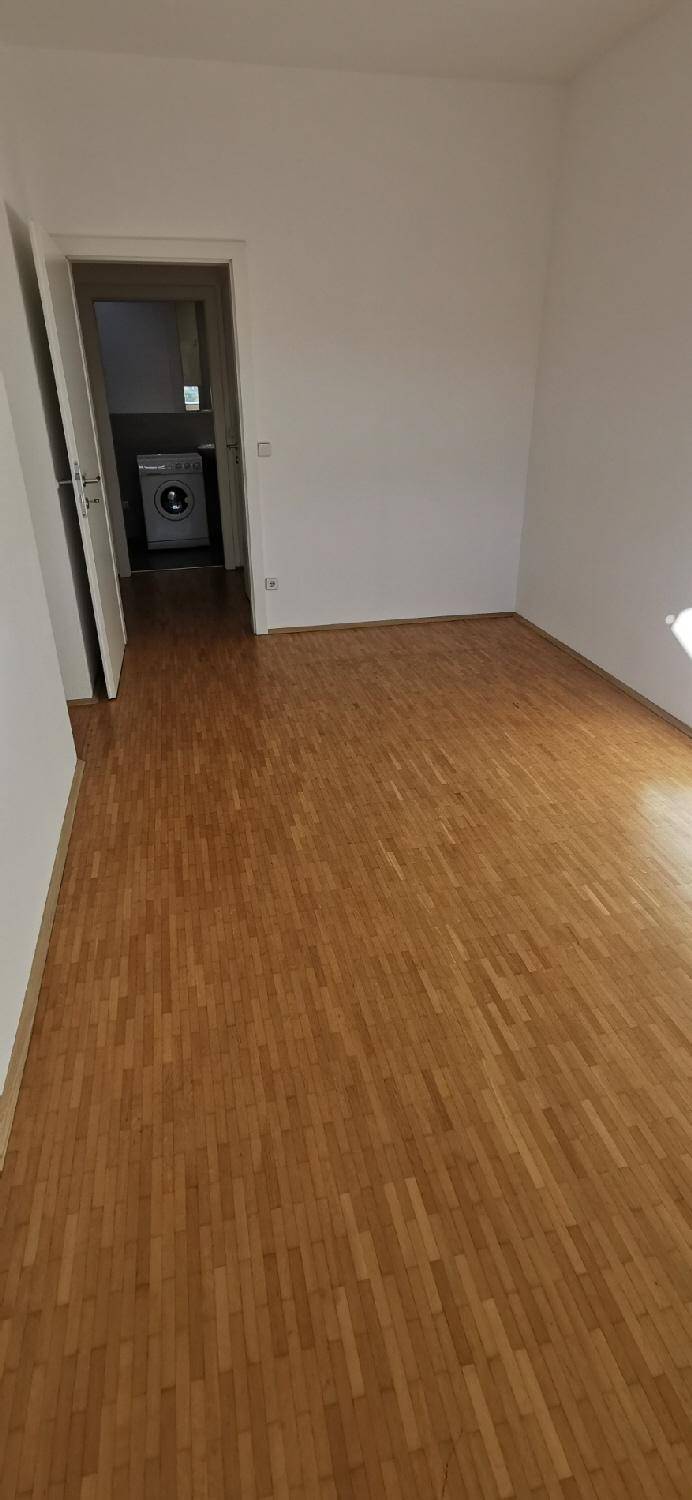 Flur mit Holzparkett, der zu einem Bereich mit Waschmaschine führt, praktisch für den Alltag.