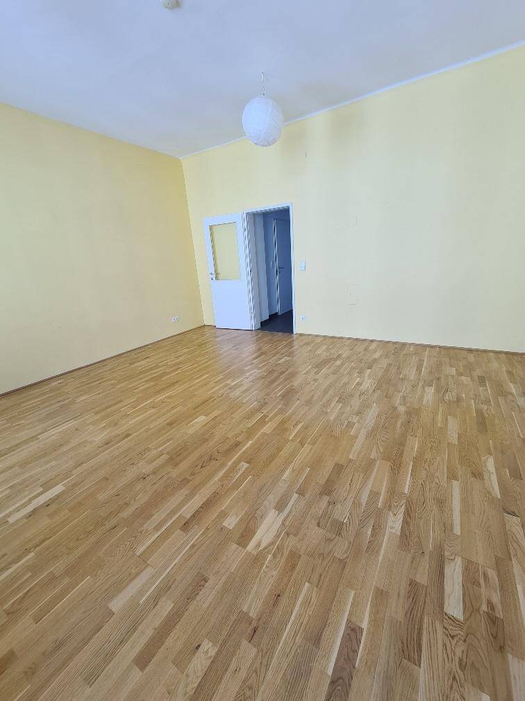 Geräumiger Raum mit hellem Holzboden und gelber Wand, ideal für Wohnzwecke.