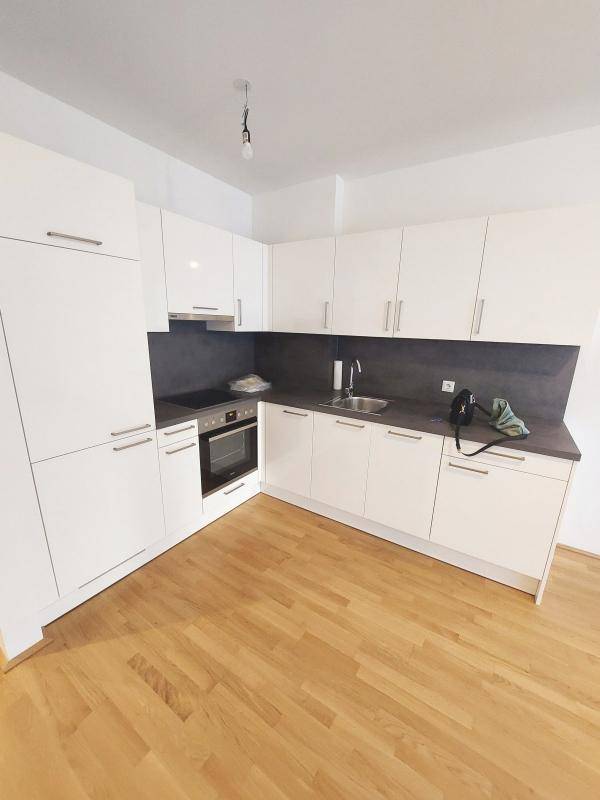 Moderne Einbauküche mit weißen Hochglanzfronten, Backofen und dunkler Arbeitsplatte.