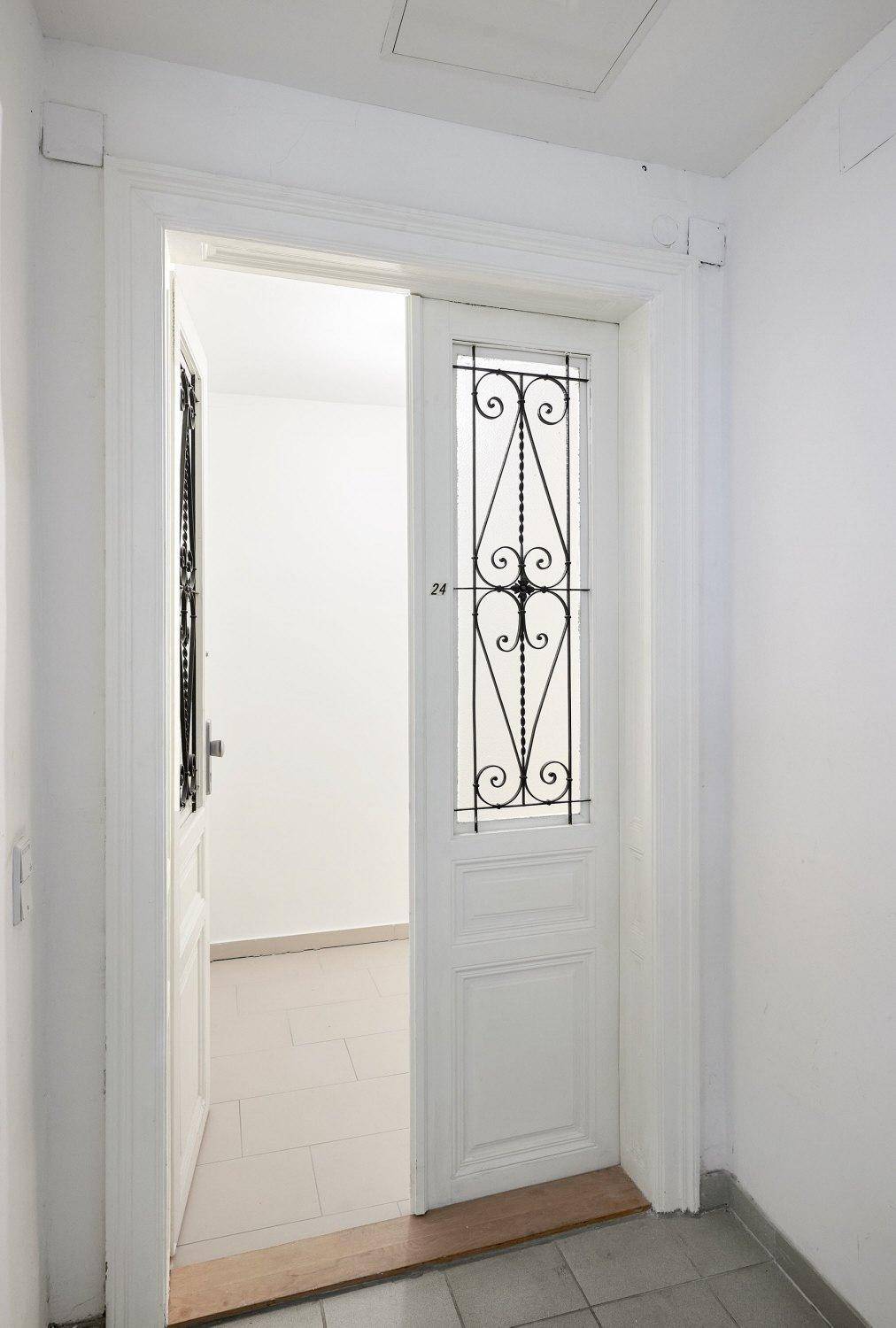 Heller Flur mit einer eleganten Eingangstür mit schmiedeeisernen Details.