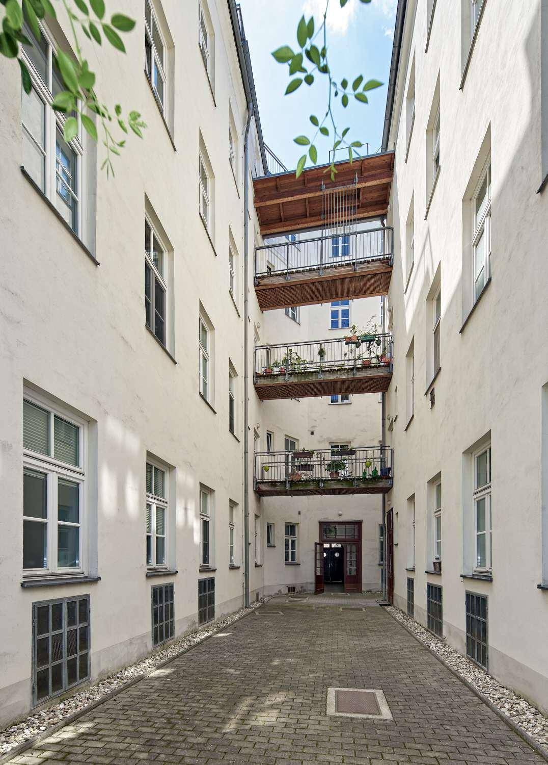 Innenhof mit mehreren Balkonen, die die Gebäude verbinden, und einem gepflasterten Weg darunter.
