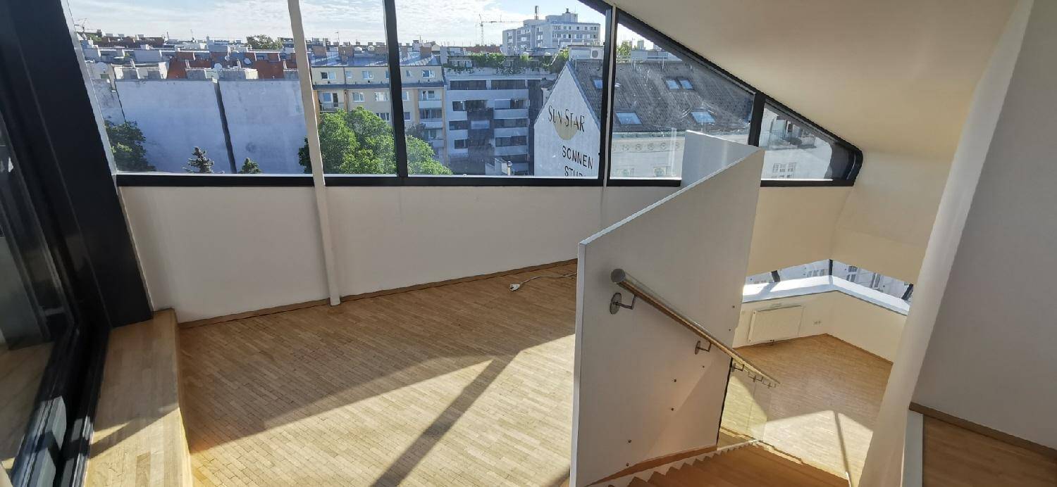 Heller Treppenaufgang mit Holzstufen und Glasgeländer, bietet einen weiten Blick über die Stadt.